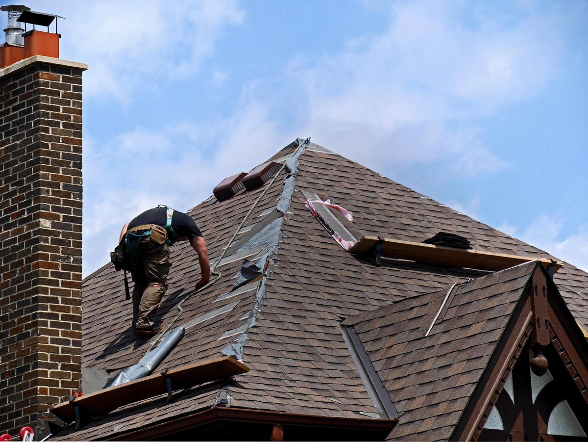 worker replacing house roofing shingles