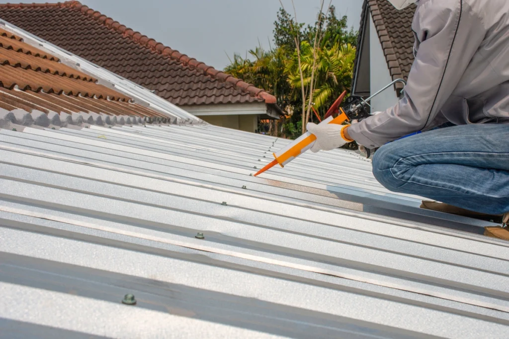 man resealing metal roof