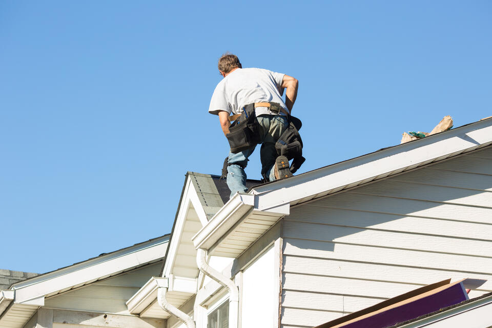bad roofing contractors-man on a white sided house wearing tool belt
