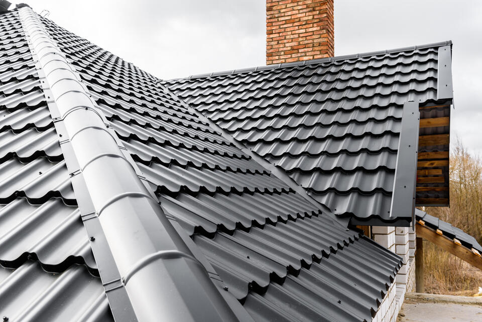 metal vs shingle roof-black metal shingle roof on a house with brick chimney