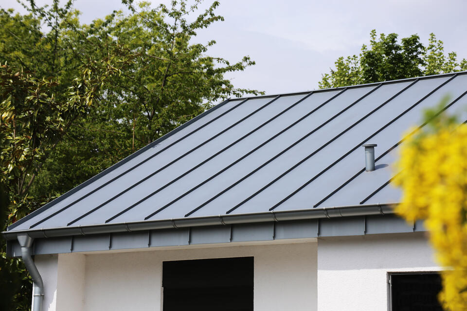 metal vs shingle roof-standing seam metal roof on a white house