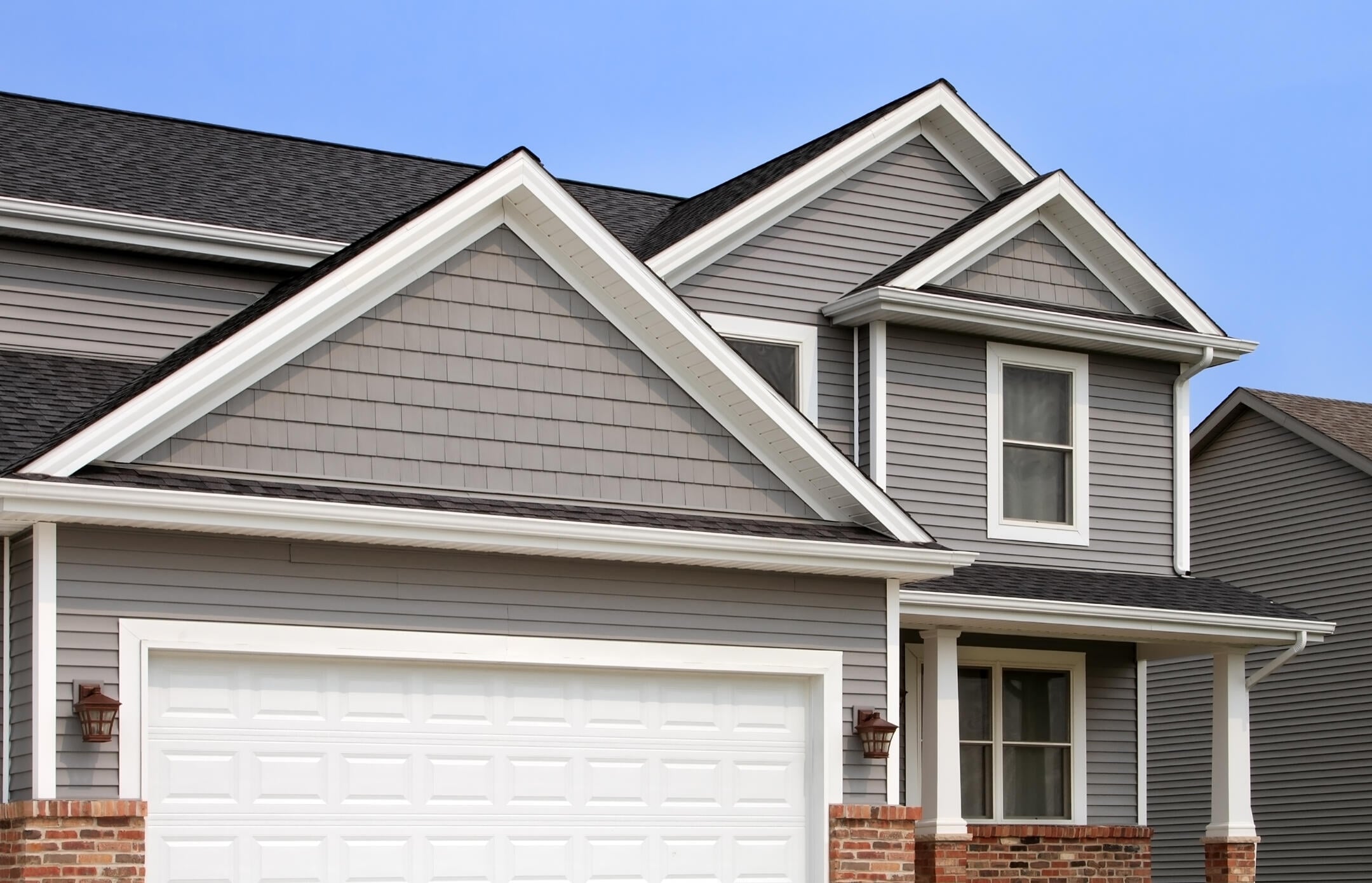 gray siding on house with brick accents and black roof