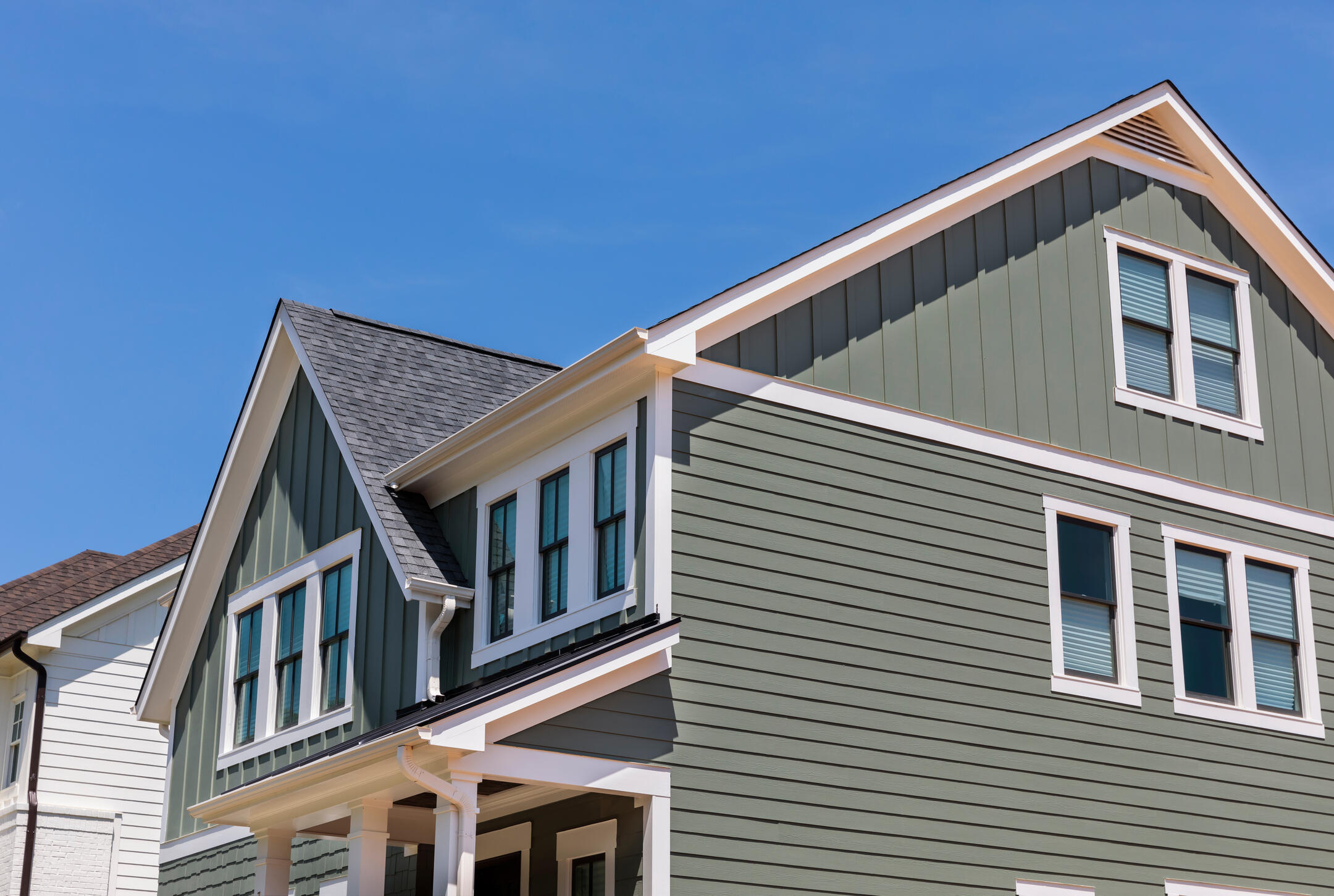 green sided house with white accents and gray shingle roof