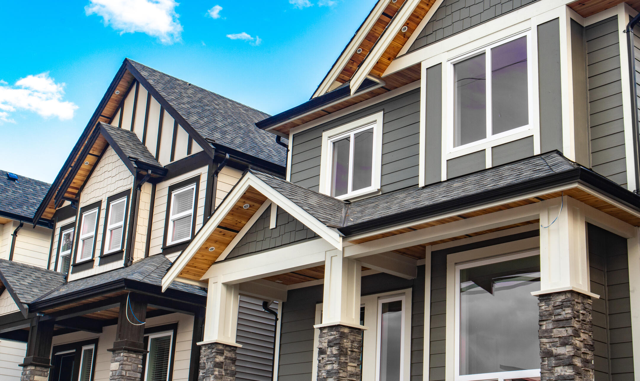 neighborhood houses with gray siding on house closest to camera and stone accents