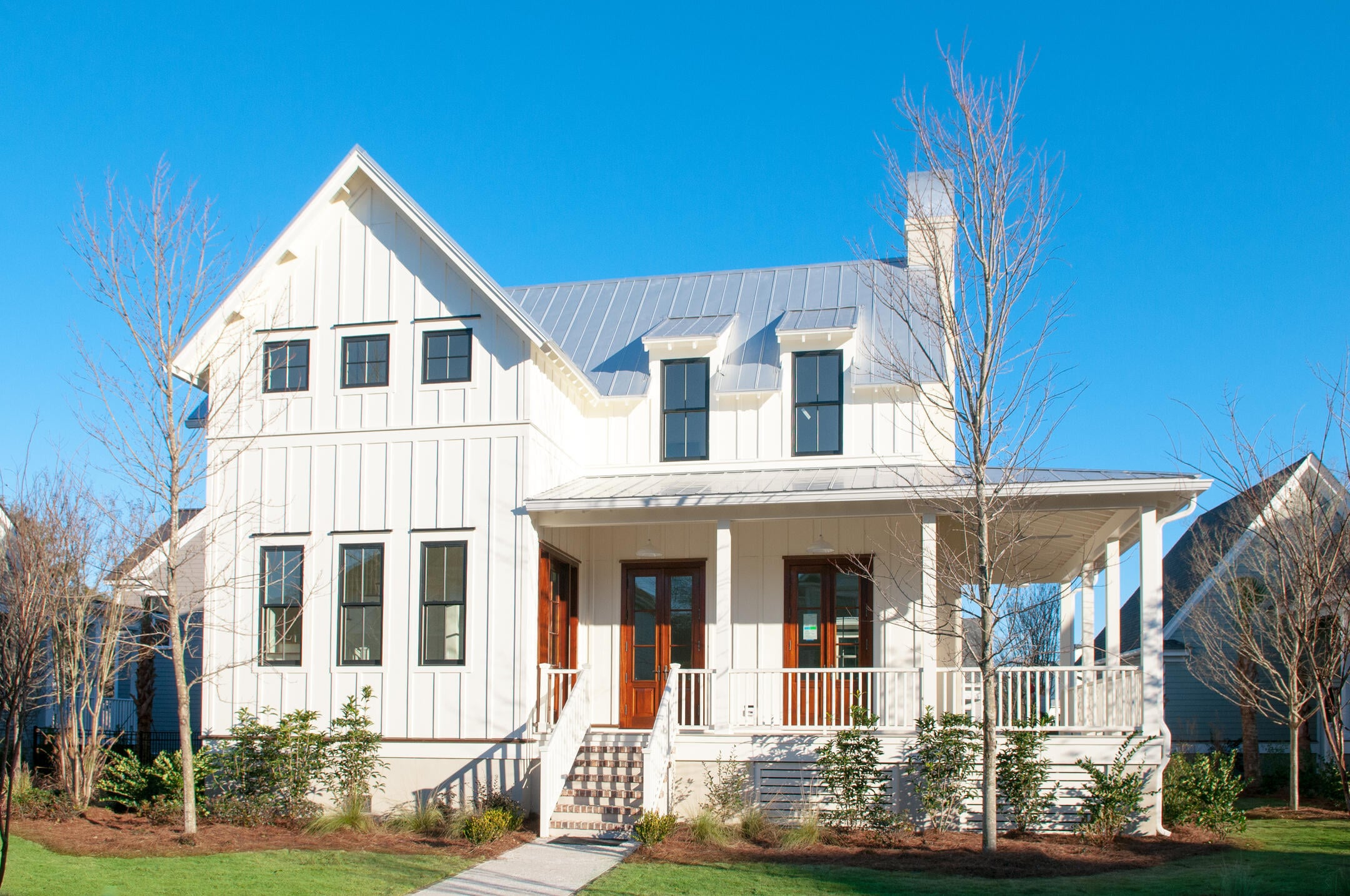 white sided house with red doors and accents near porch
