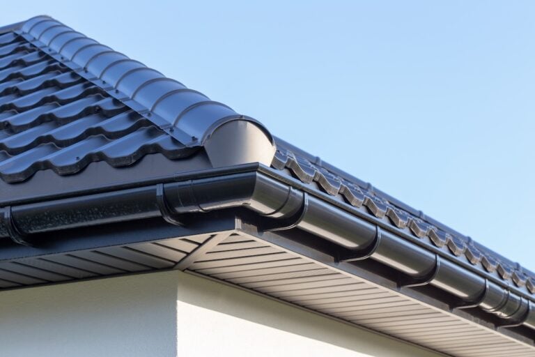 Corner of the new modern house with gutter, roof, wall under blue sky