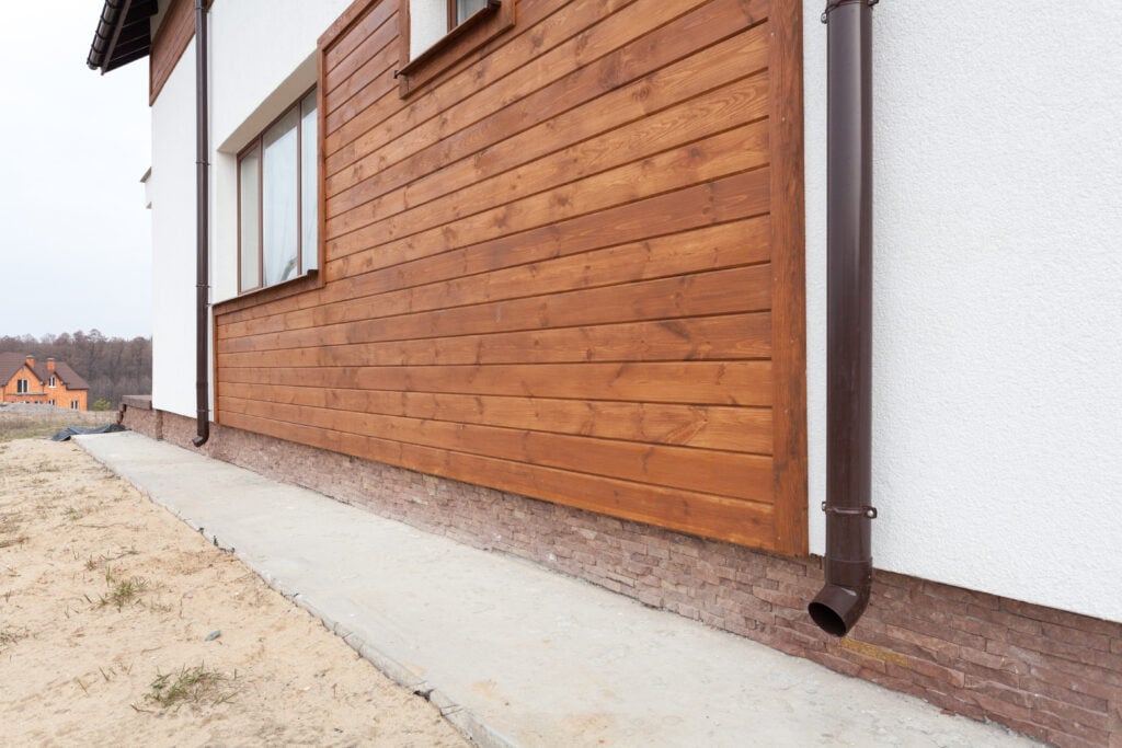 New brown copper gutter in house with white wall and wooden planks