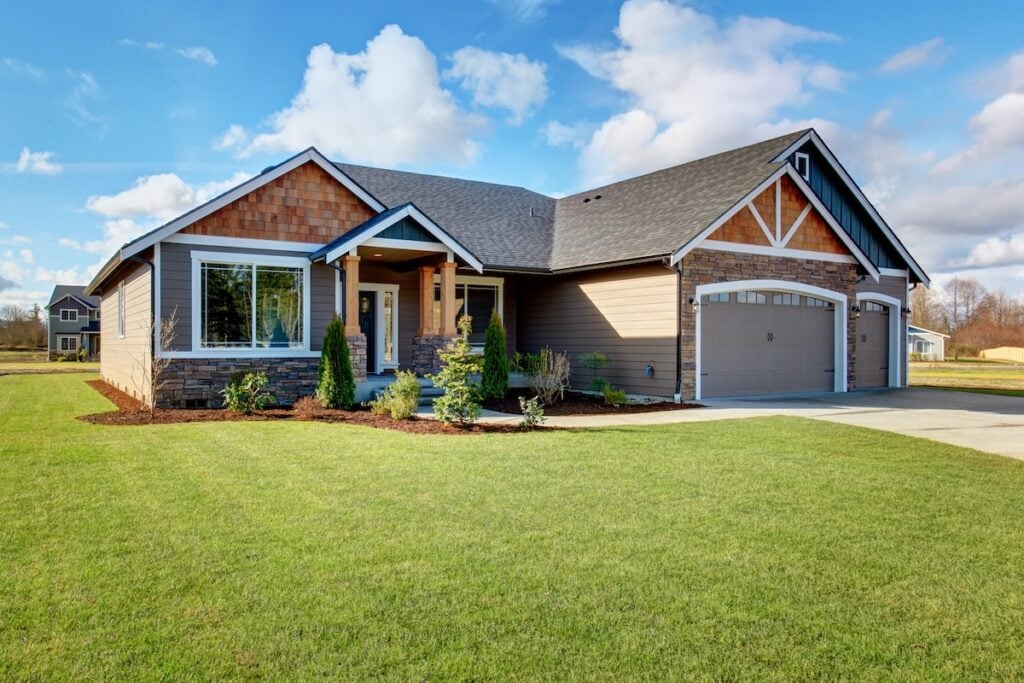 Large modern house with walkway and lots of grass.