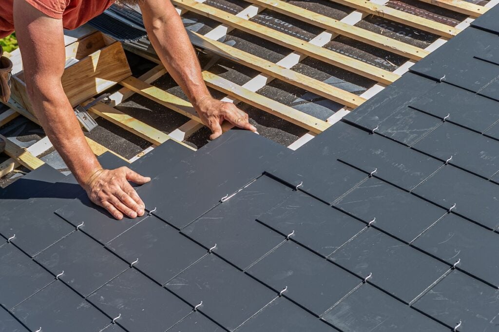 types of roof slates Craftsmen are installing a slate roof home.Professional roof workers installing roof for a old house .Working on rooftop.