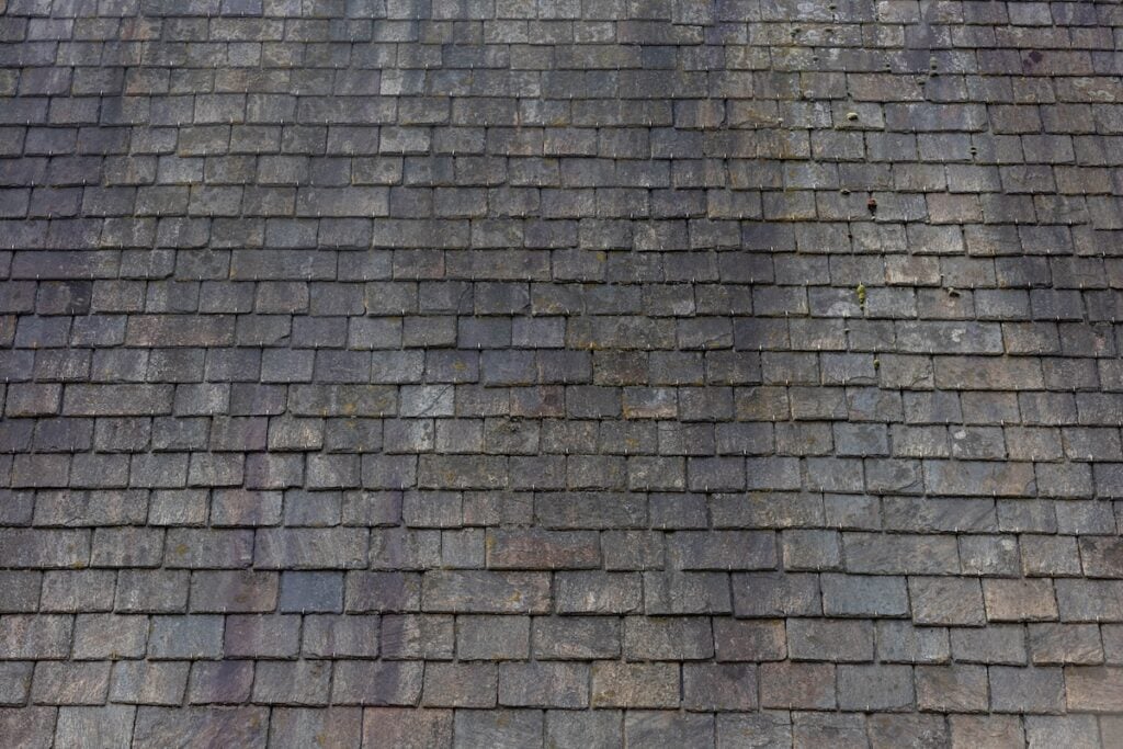 black streaks on roof Old dark brown stone tiles covered with moss and rust stain on brick roof, Shingles texture, Abstract geometric pattern background, Details of roof top material.