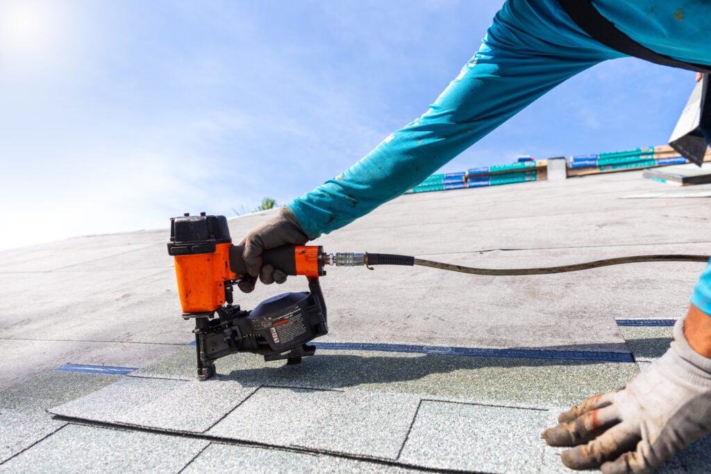 where to nail shingles roofer installing roof shingles with roofing nailer.