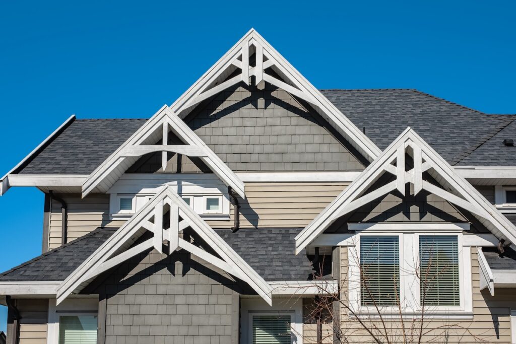 gaf vs certainteed Roof shingles on top of the house against blue sky. Dark asphalt tiles on the roof background. black shingles, roof tile. 