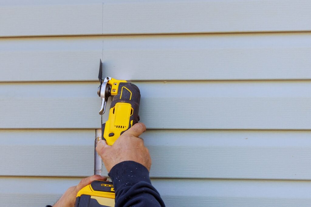 vinyl siding repair cost Reconstruction of house involves removal damaged vinyl siding with a multi tool