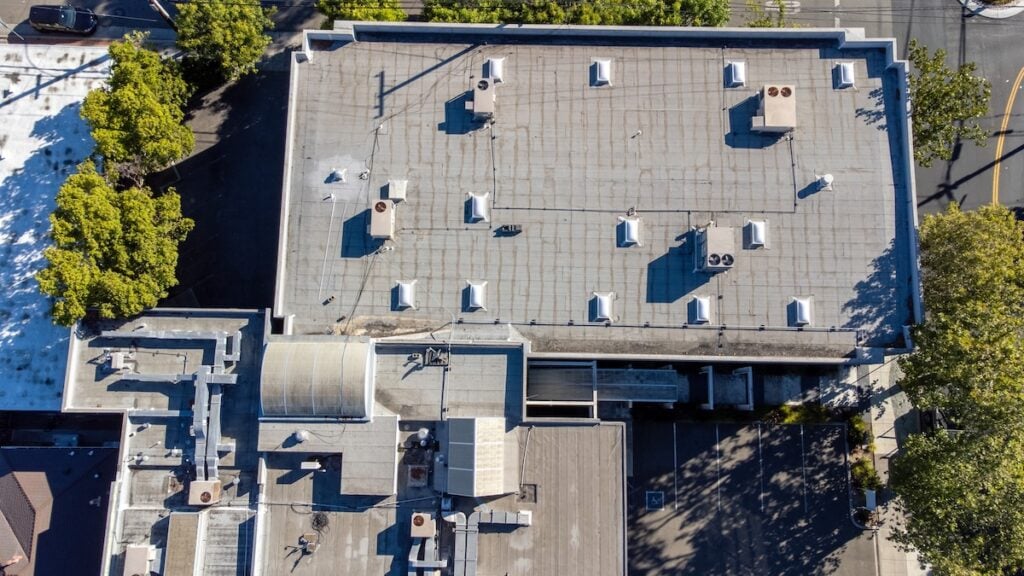 Aerial view of a flat commercial rooftop with air vents and air conditioning HVAC units