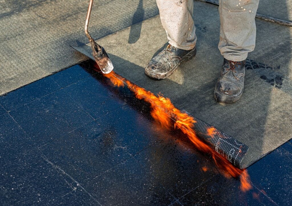 Roof waterproofing with bituminous membrane being installed
