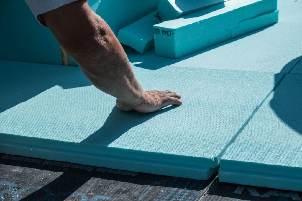 XPS polystyrene insulation boards placed by a worker on the flat roof