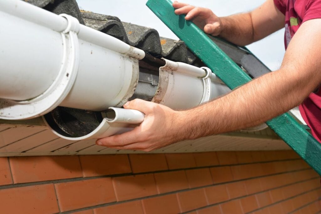 Commercial gutter repair worker installing white water system