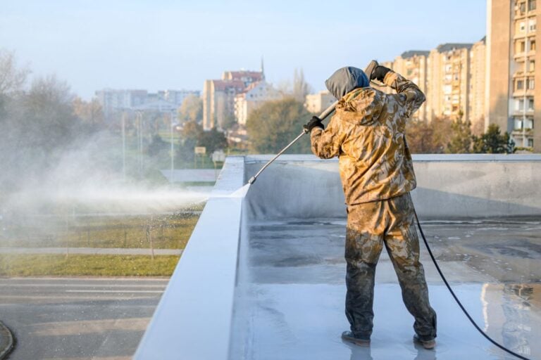 commercial roof cleaning worker using hose on top