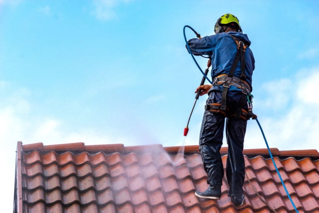 commercial roof cleaning worker using security water hose
