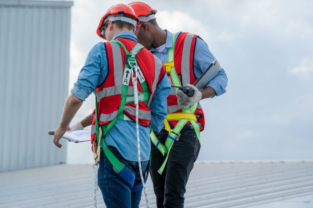 commercial roof warranty two construction workers talking about papers on top of building