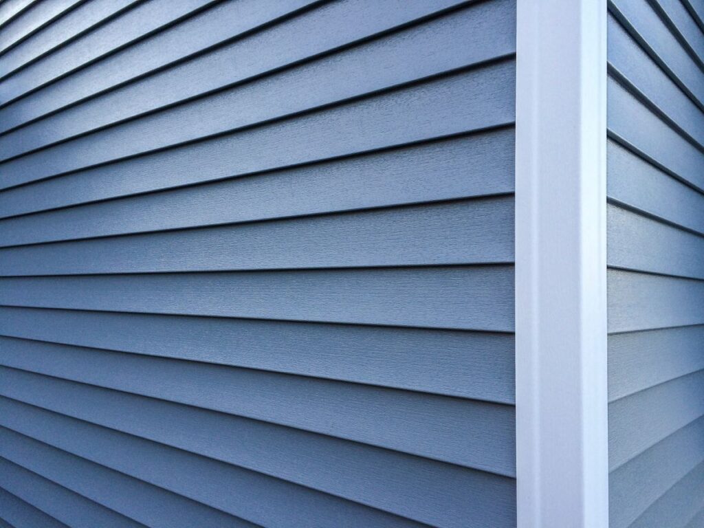 Blue vinyl siding with white trim on the outside wall of a new home