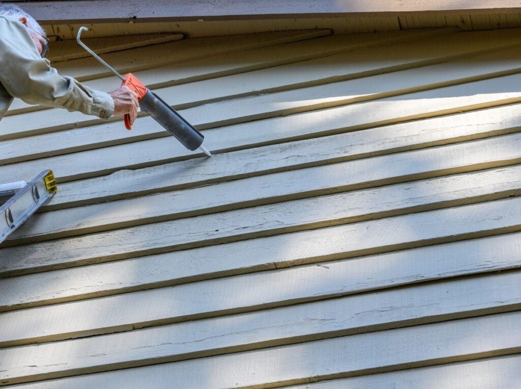 Man repairing wood siding on the exterior of a residential building